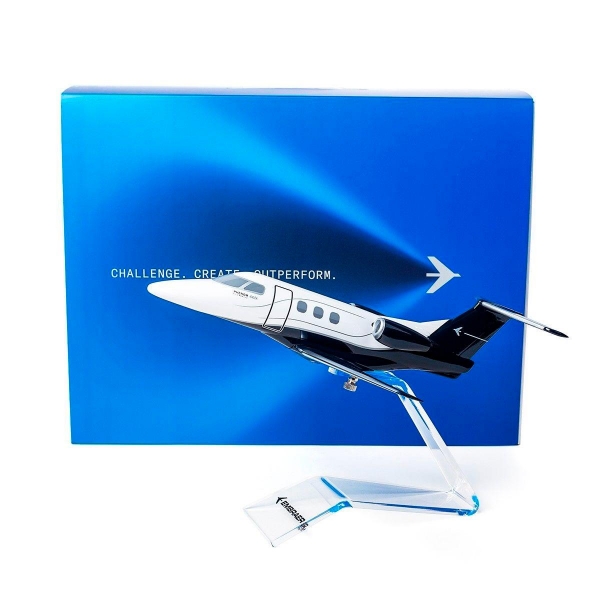1:50 scale Embraer Phenom 100EX jet model on acrylic stand with branded gift box in background.